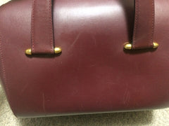 Vintage Cartier classic wine, bordeaux leather handbag purse in unique shape with bullet design gold hardware at handles. Must de Cartier