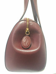 Vintage Cartier classic wine, bordeaux leather handbag purse in unique shape with bullet design gold hardware at handles. Must de Cartier