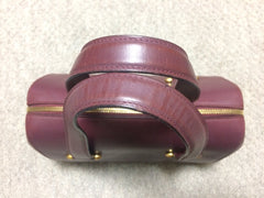 Vintage Cartier classic wine, bordeaux leather handbag purse in unique shape with bullet design gold hardware at handles. Must de Cartier
