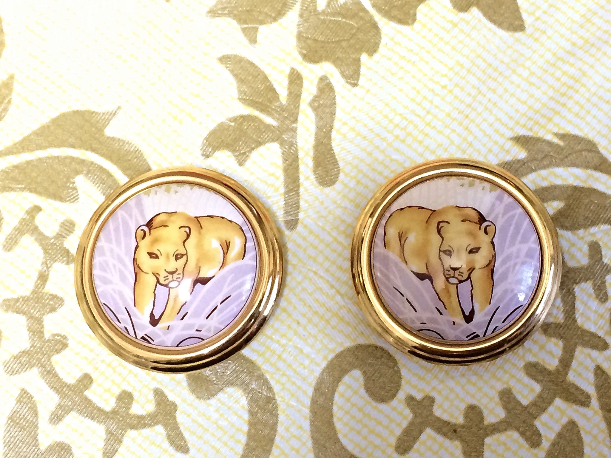 Vintage Hermes cloisonne golden round earrings with female lion design on white and light grey. Great gift idea