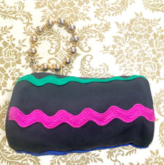 Vintage Moschino by Redwall tube shape black pouch bag with pink, green, and blue wave trimming and gold tone ball design handle. Rare, chic and mod pouch bag.