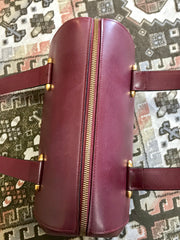 Vintage Cartier classic wine, bordeaux leather handbag purse in unique shape with bullet design gold hardware at handles. Must de Cartier