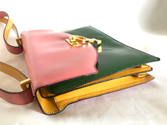 Vintage MOSCHINO pink, green, and yellow patent enamel leather shoulder bag with golden men symbol motif at closure. Masterpiece by Red wall