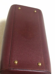 Vintage Cartier classic wine, bordeaux leather handbag purse in unique shape with bullet design gold hardware at handles. Must de Cartier