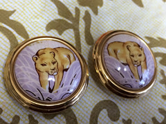 Vintage Hermes cloisonne golden round earrings with female lion design on white and light grey. Great gift idea