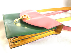 Vintage MOSCHINO pink, green, and yellow patent enamel leather shoulder bag with golden men symbol motif at closure. Masterpiece by Red wall
