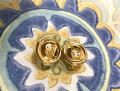 Vintage Givenchy golden round shape earrings with embossed logo mark. Classic jewelry piece.
