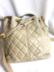 Vintage CHANEL beige quilted lamb leather hobo bucket shoulder bag with drawstrings and golden CC mark ball.