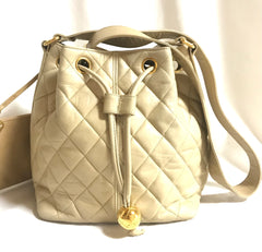 Vintage CHANEL beige quilted lamb leather hobo bucket shoulder bag with drawstrings and golden CC mark ball.
