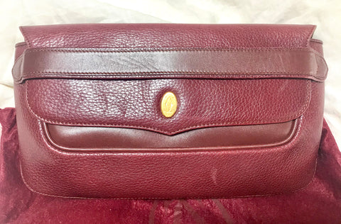 Vintage Cartier wine leather clutch bag with gold tone logo motif. Classic purse from must de Cartier Collection.
