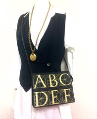 Vintage Paloma Picasso black canvas and leather combo shoulder bag with golden A B C D E F and S T V X Y letter print.