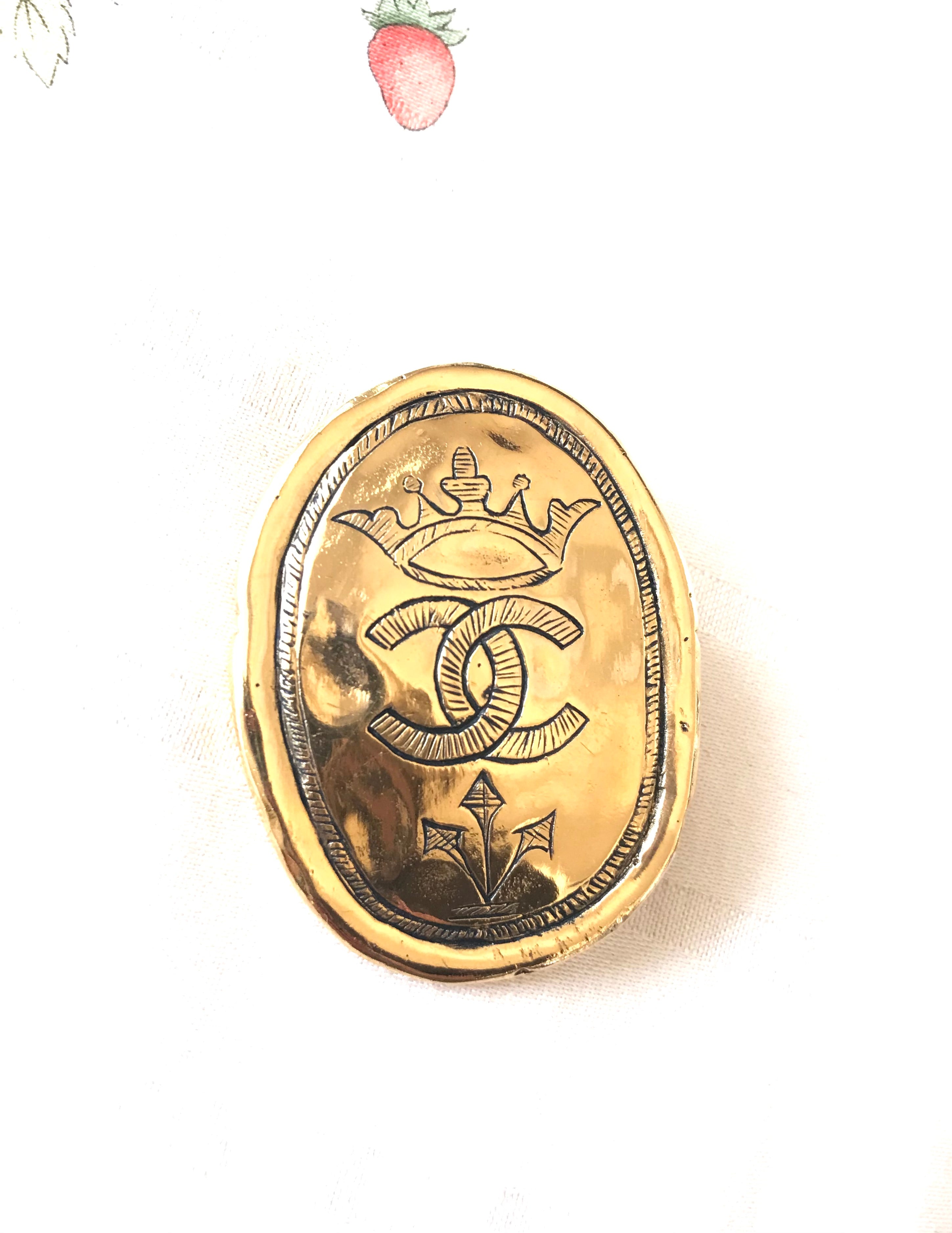 Vintage CHANEL gold tone large brooch in oval coin shape with CC logo and crown embossed motif. Rare masterpiece jewelry. Best gift
