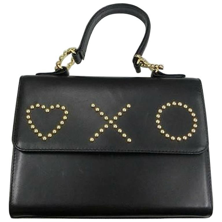 Vintage MOSCHINO black leather handbag in classic kelly purse style with golden studded heart, X, and O, playful motifs. Perfect daily bag